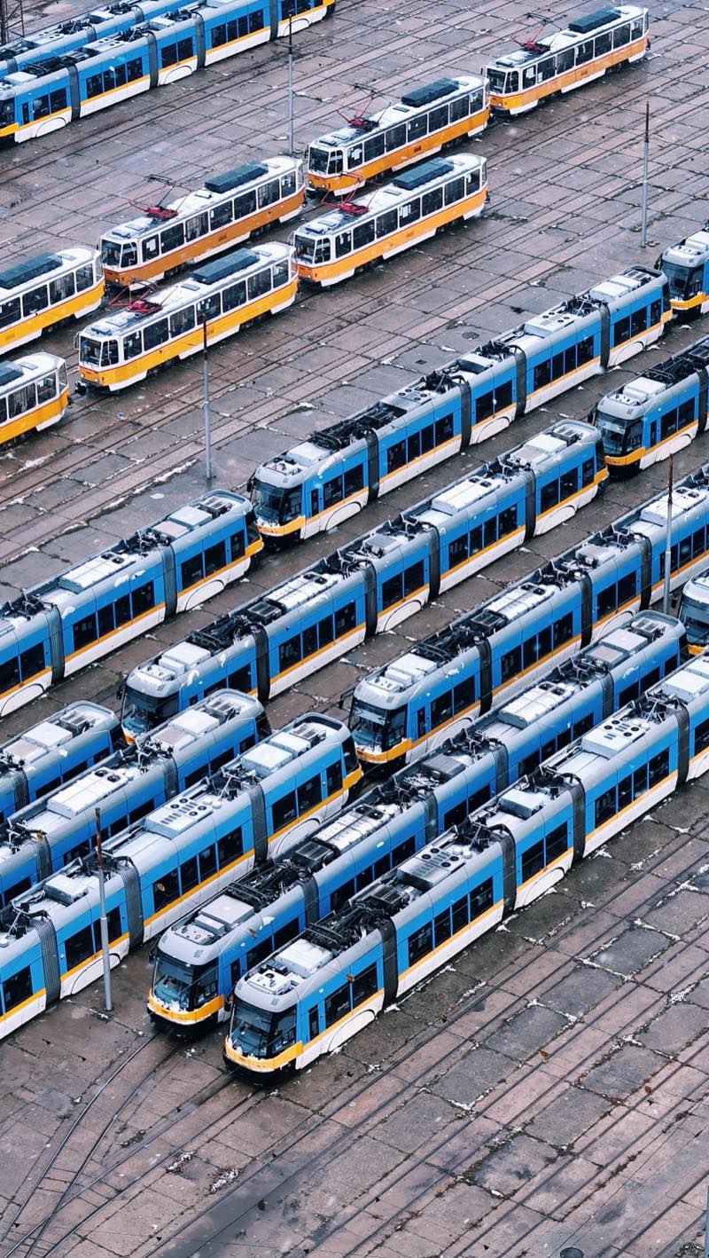 Blue and white trams parked in rows, with yellow trams behind, seen from above.
