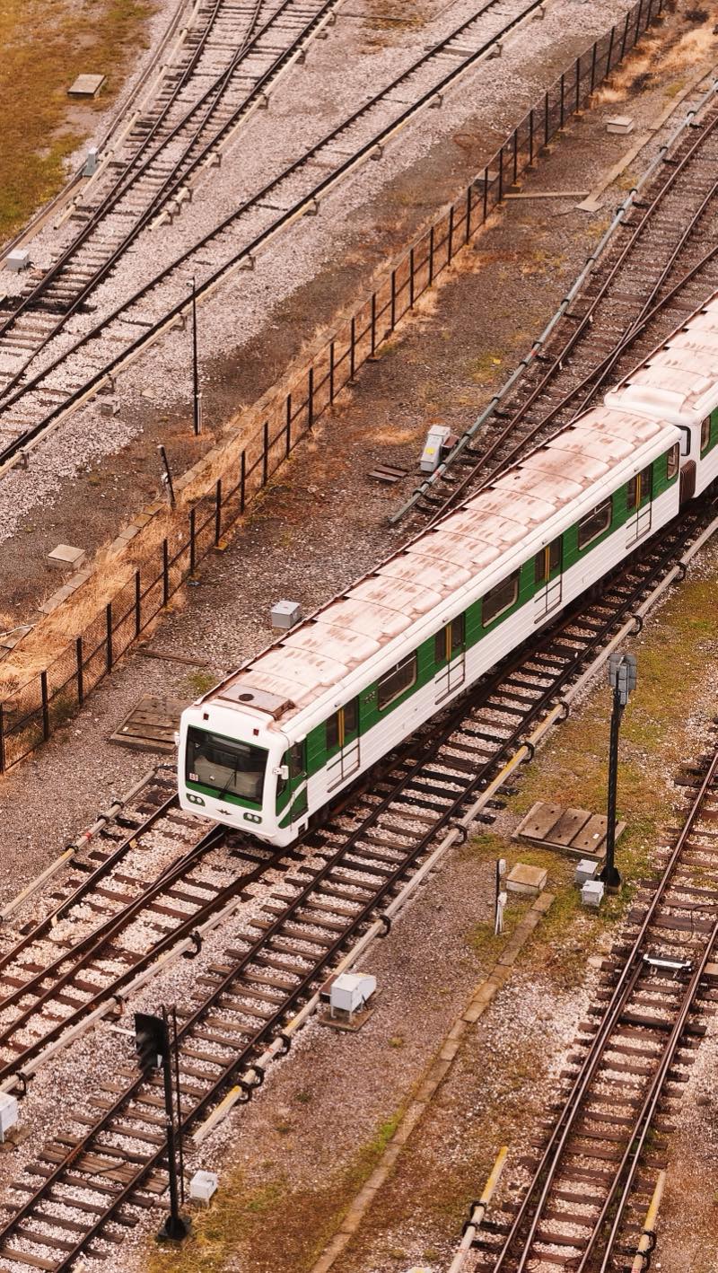 Green and white metro train on tracks in a depot yard.