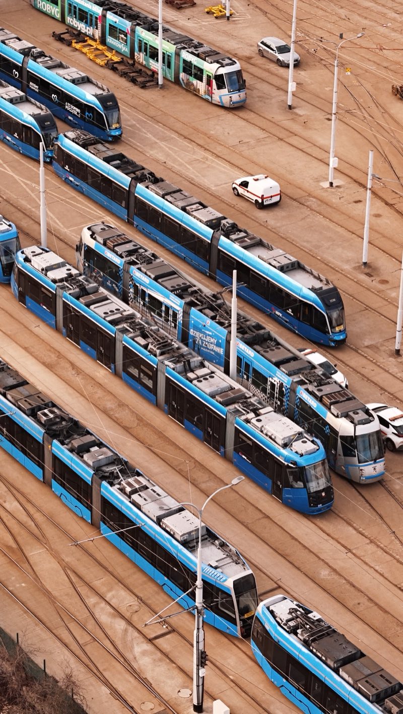 Rows of blue articulated trams parked on curving depot tracks.
